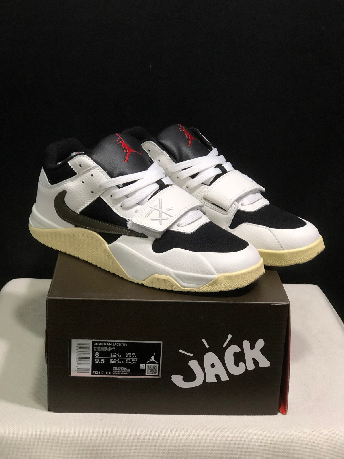 Pair of white and black Jordan Jumpman Jack TR sneakers displayed on a branded box; the box label shows sample size EU 43 and style code FZ8117 110.