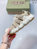 Side view of the beige closed-toe sandal showing adjustable straps, open side panels, and the segmented sole.