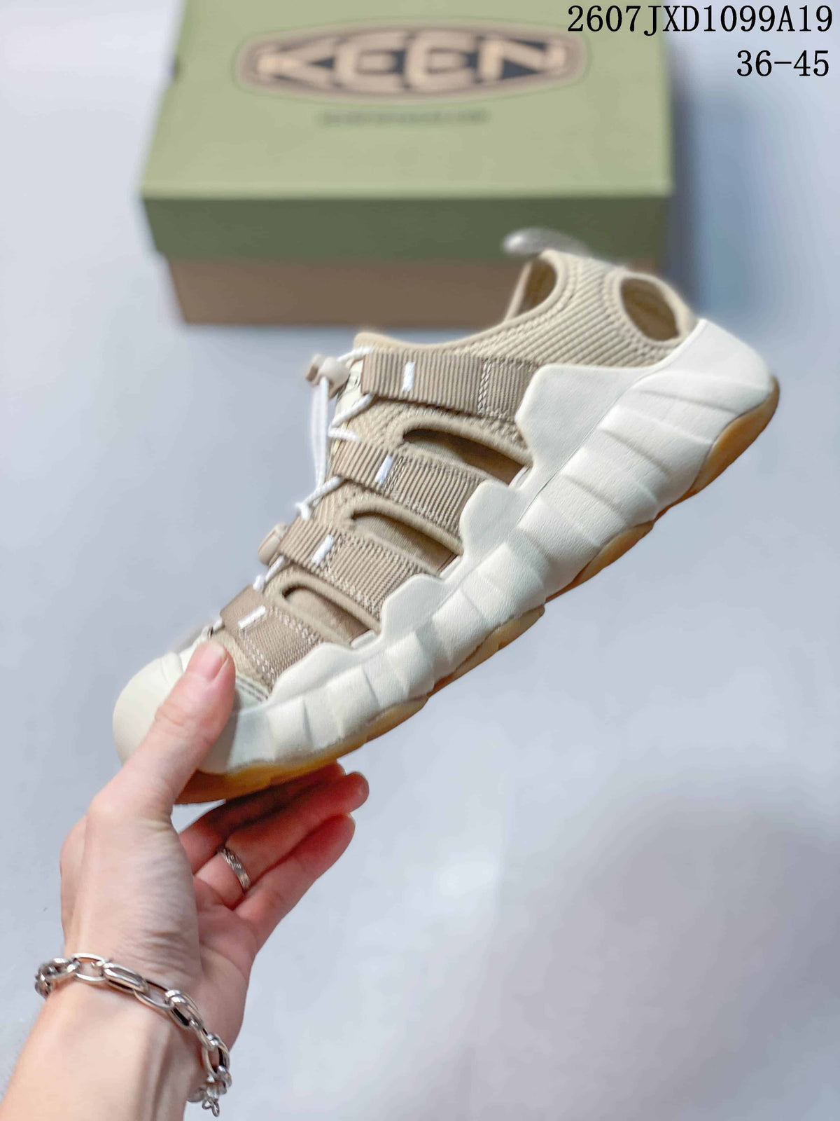 Side view of the beige closed-toe sandal showing adjustable straps, open side panels, and the segmented sole.