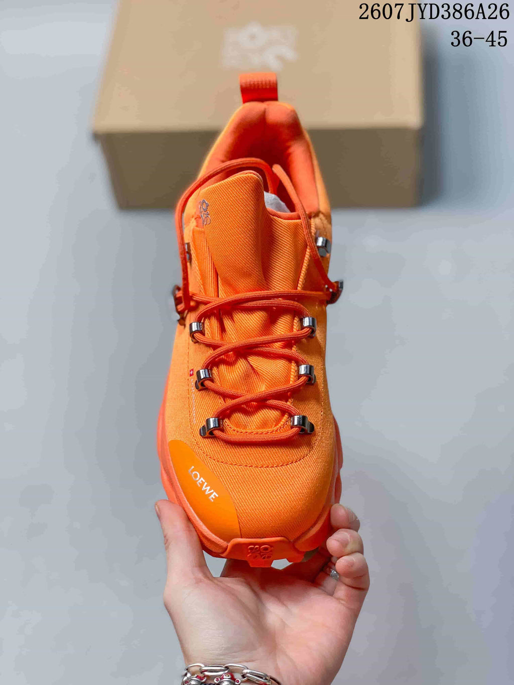 Top view of an orange sneaker showing the rounded toe, layered lace system, metallic-style lace hardware, and LOEWE branding.