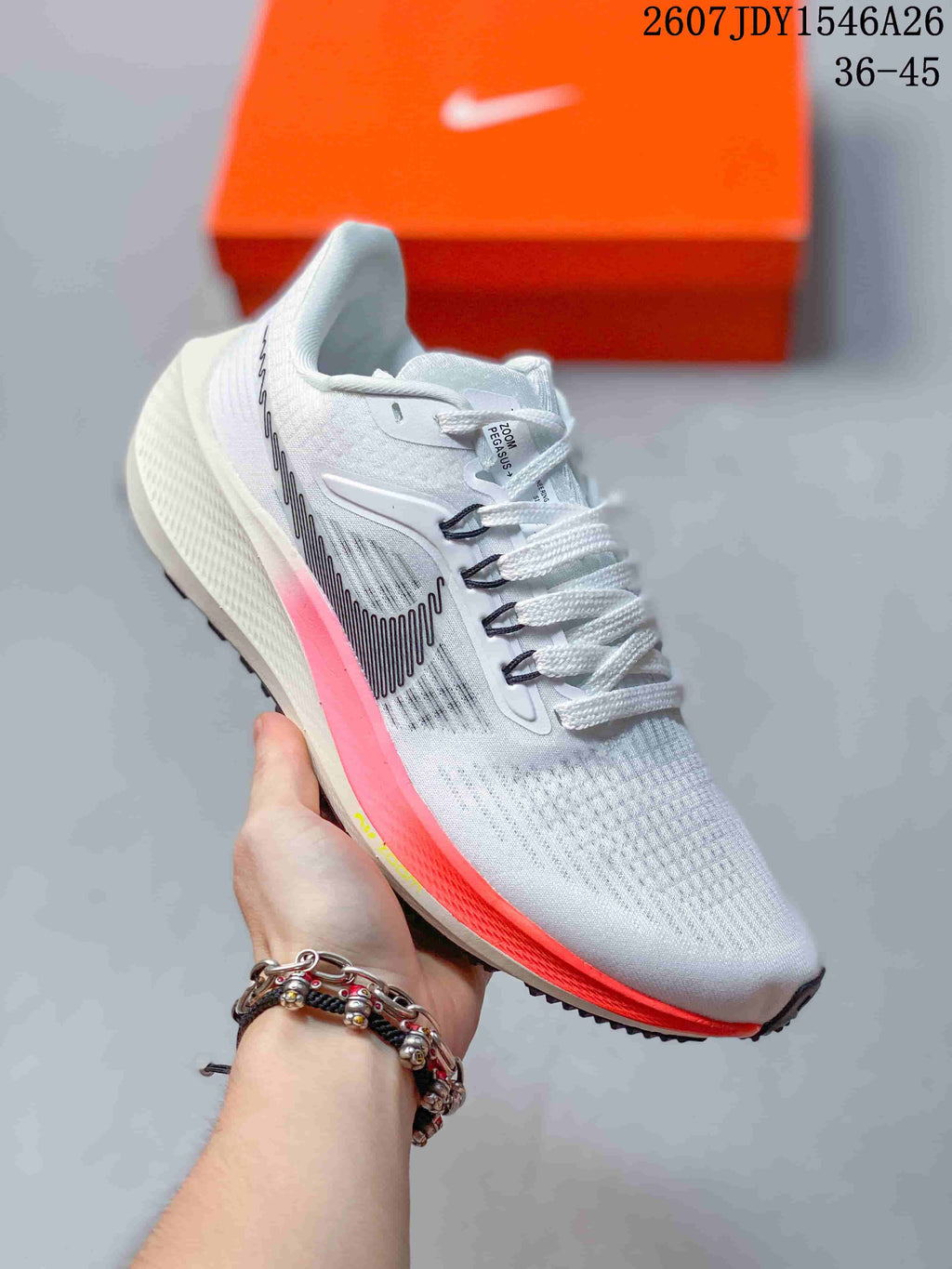 White Nike Air Zoom Pegasus 39 sneaker with a black patterned side logo and bright pink and red midsole accents.