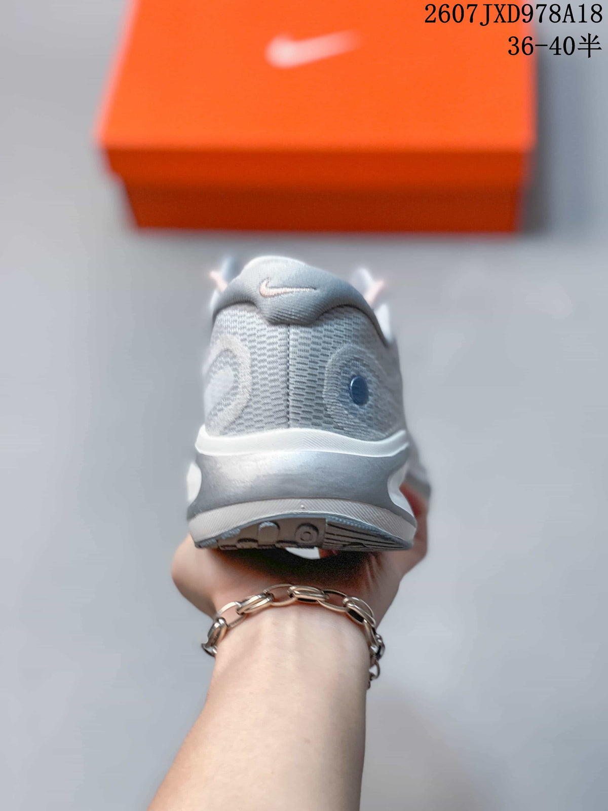 Rear view of a light gray Nike Journey Run shoe showing the padded collar, heel structure and textured outsole.