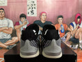 Rear view of black sneakers with silver patterned panels and light-colored midsoles