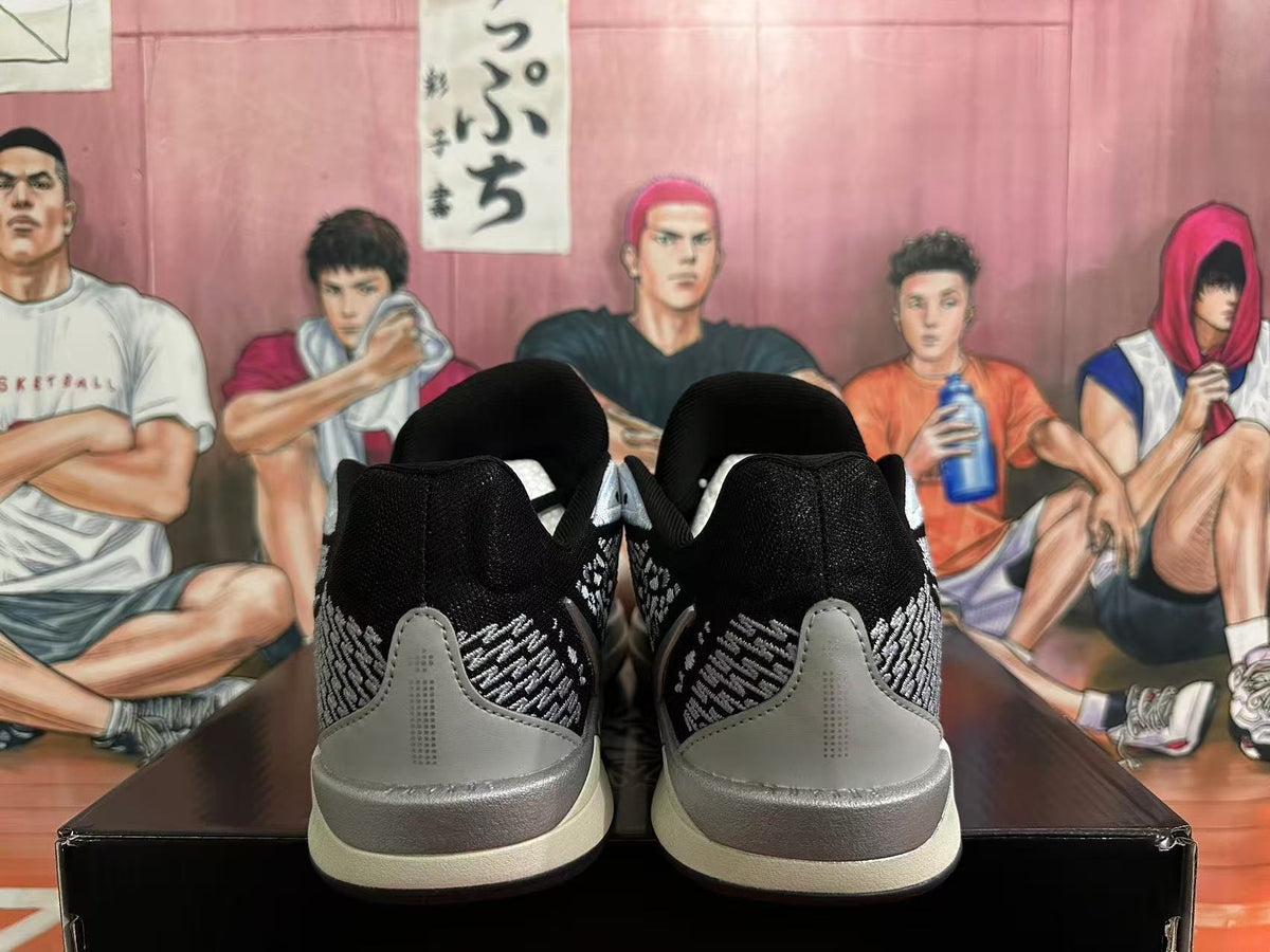 Rear view of black sneakers with silver patterned panels and light-colored midsoles