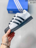 Side view of a white and black low-top Superstar sneaker showing the three side stripes and flat sole.