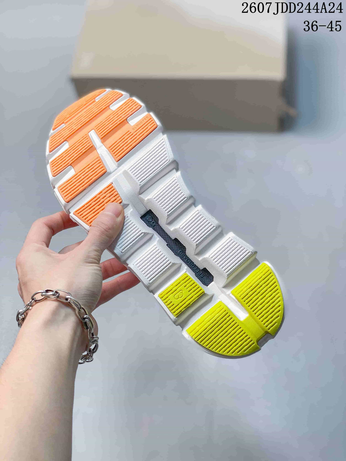 Underside view of the sneaker showing a segmented white outsole with orange and neon yellow-green traction sections.