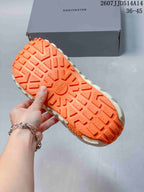 Close-up of the orange outsole showing a chunky geometric tread pattern and raised traction blocks.