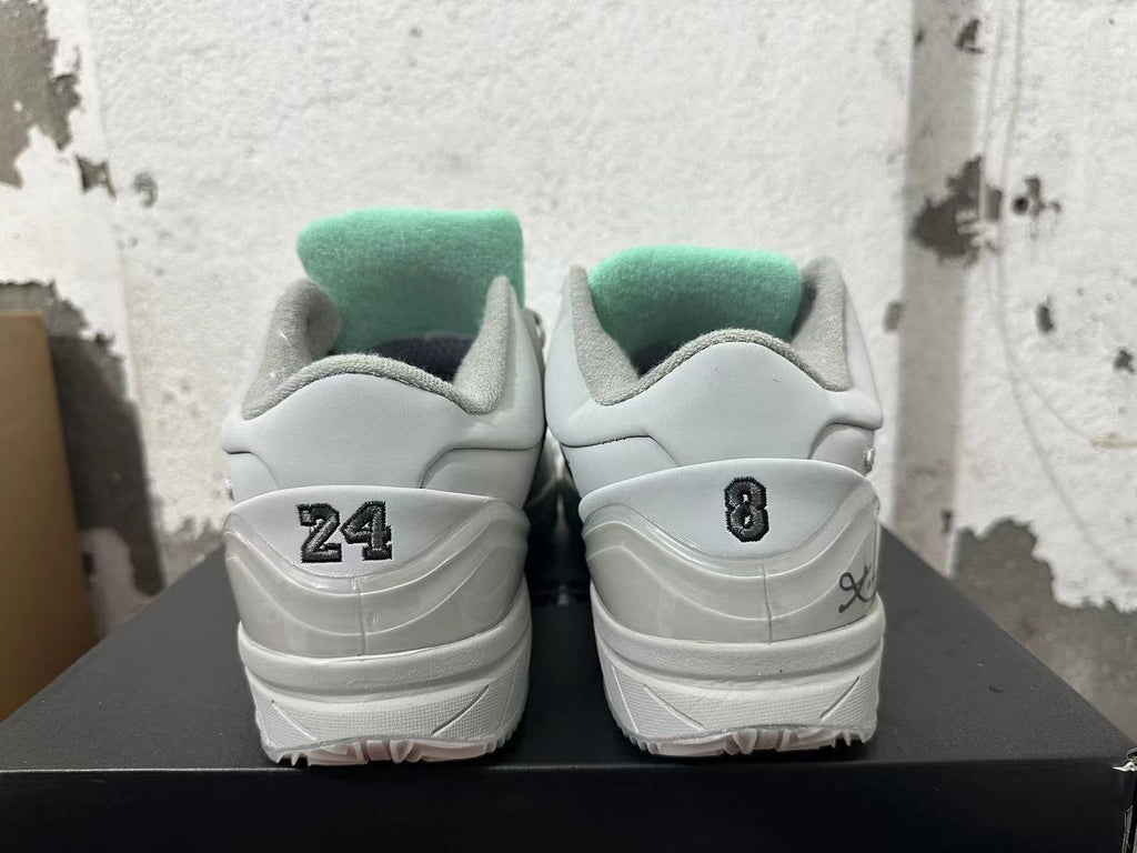 Rear view of light grey and white basketball shoes with number details at the heels and teal tongue lining.
