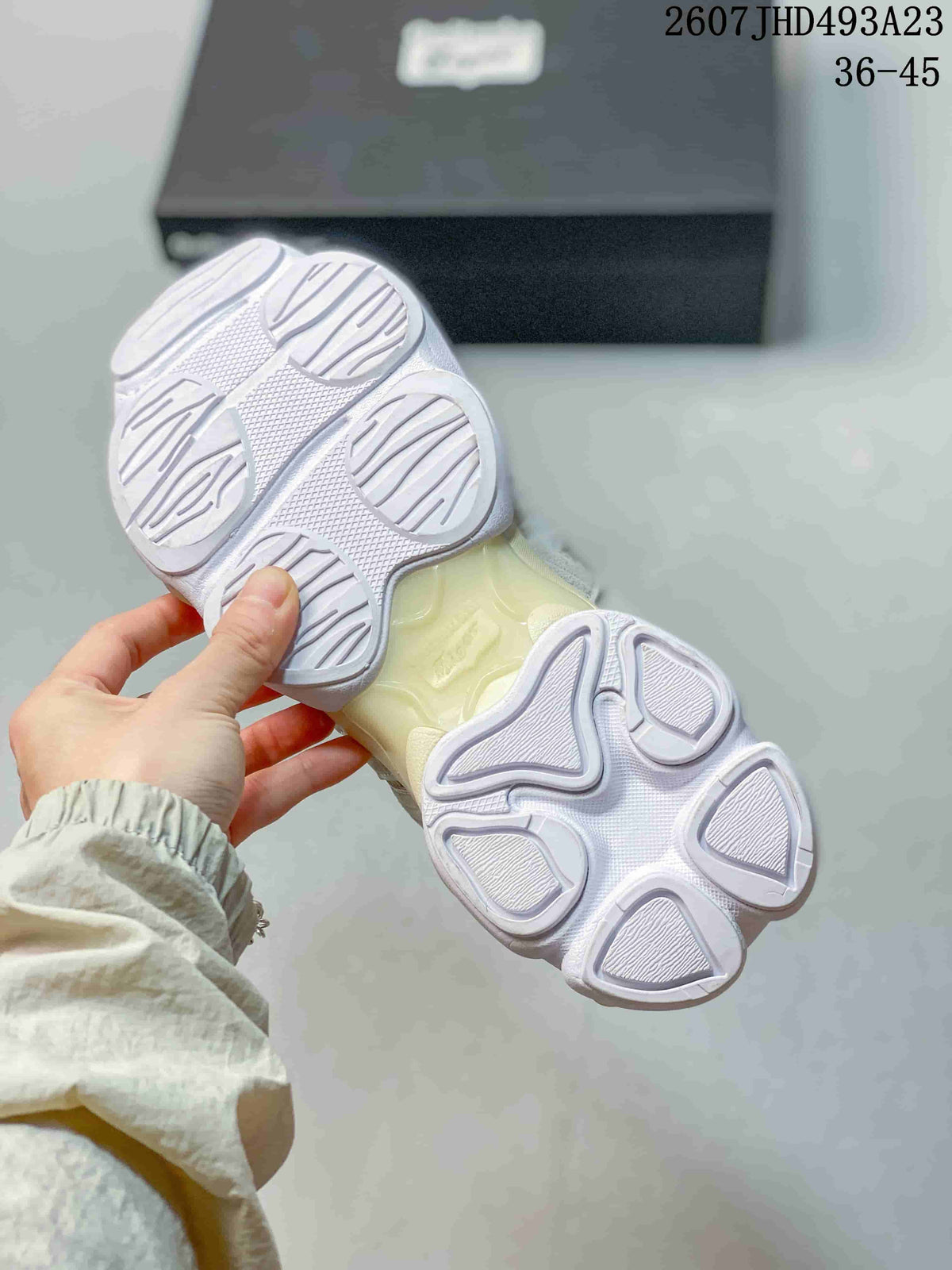 Underside view of the sneaker showing the segmented white outsole and cream-toned midsole section.