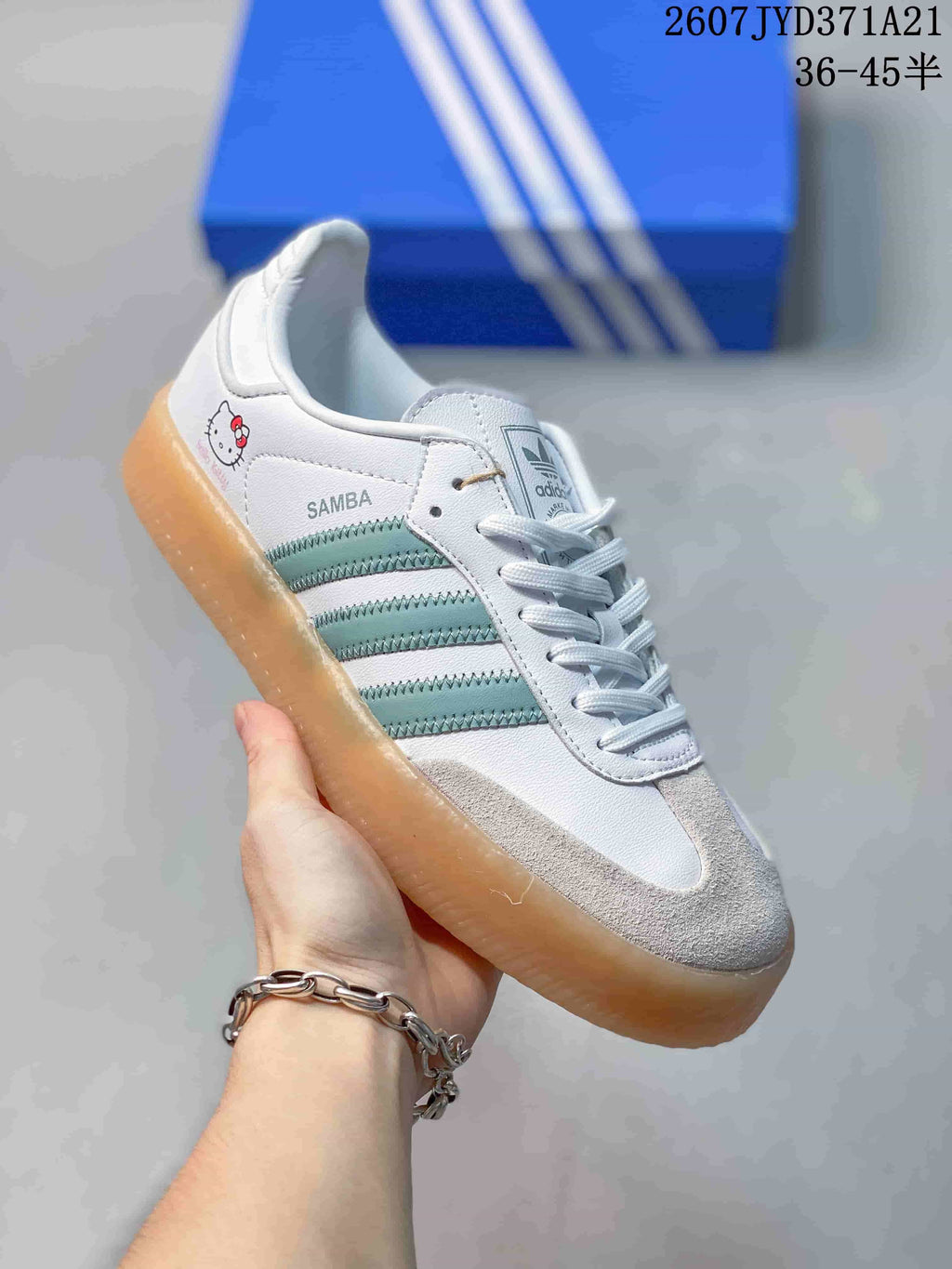 Angled side view showing the Samba marking, mint-green stripes, gum sole, and Hello Kitty heel graphic.