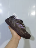 Close-up view of a dark brown Balenciaga sneaker showing the side panels, light-purple accents, black laces, and rubber outsole.