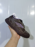 Close-up view of a dark brown Balenciaga sneaker showing the side panels, light-purple accents, black laces, and rubber outsole.