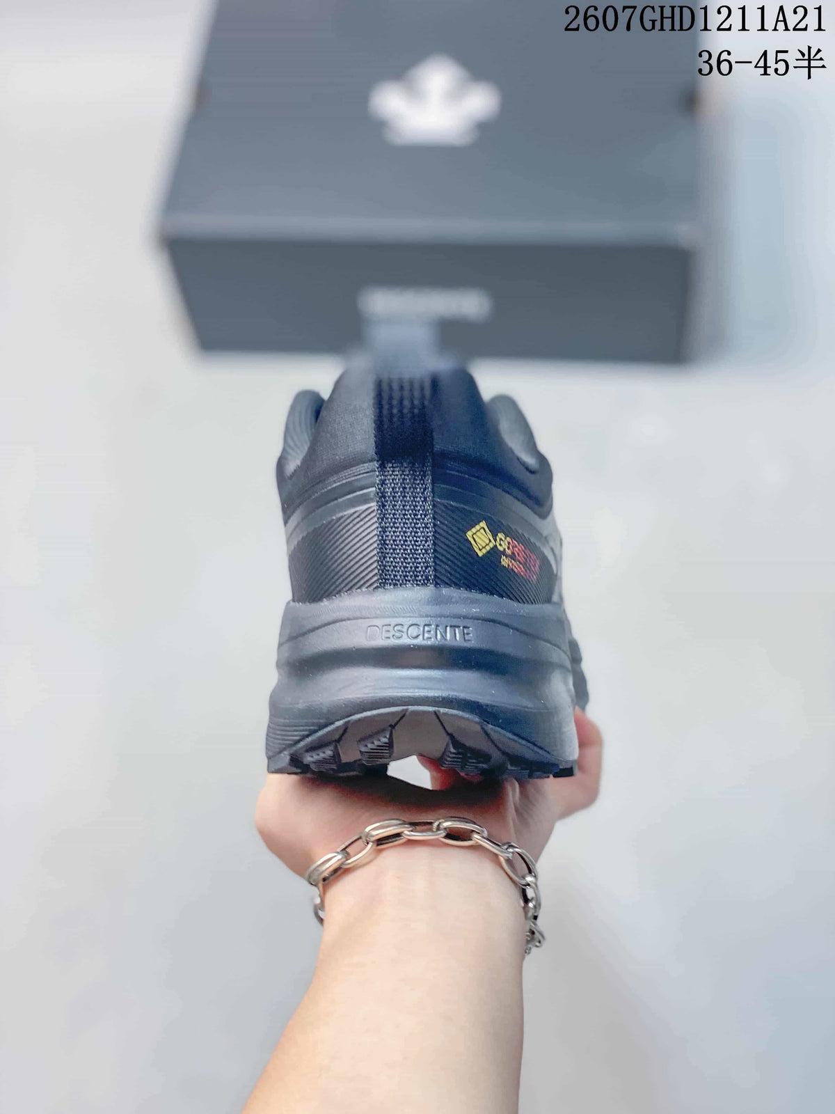 Rear view of the black sneaker showing the padded heel, pull tab, DESCENTE branding, and textured outsole.