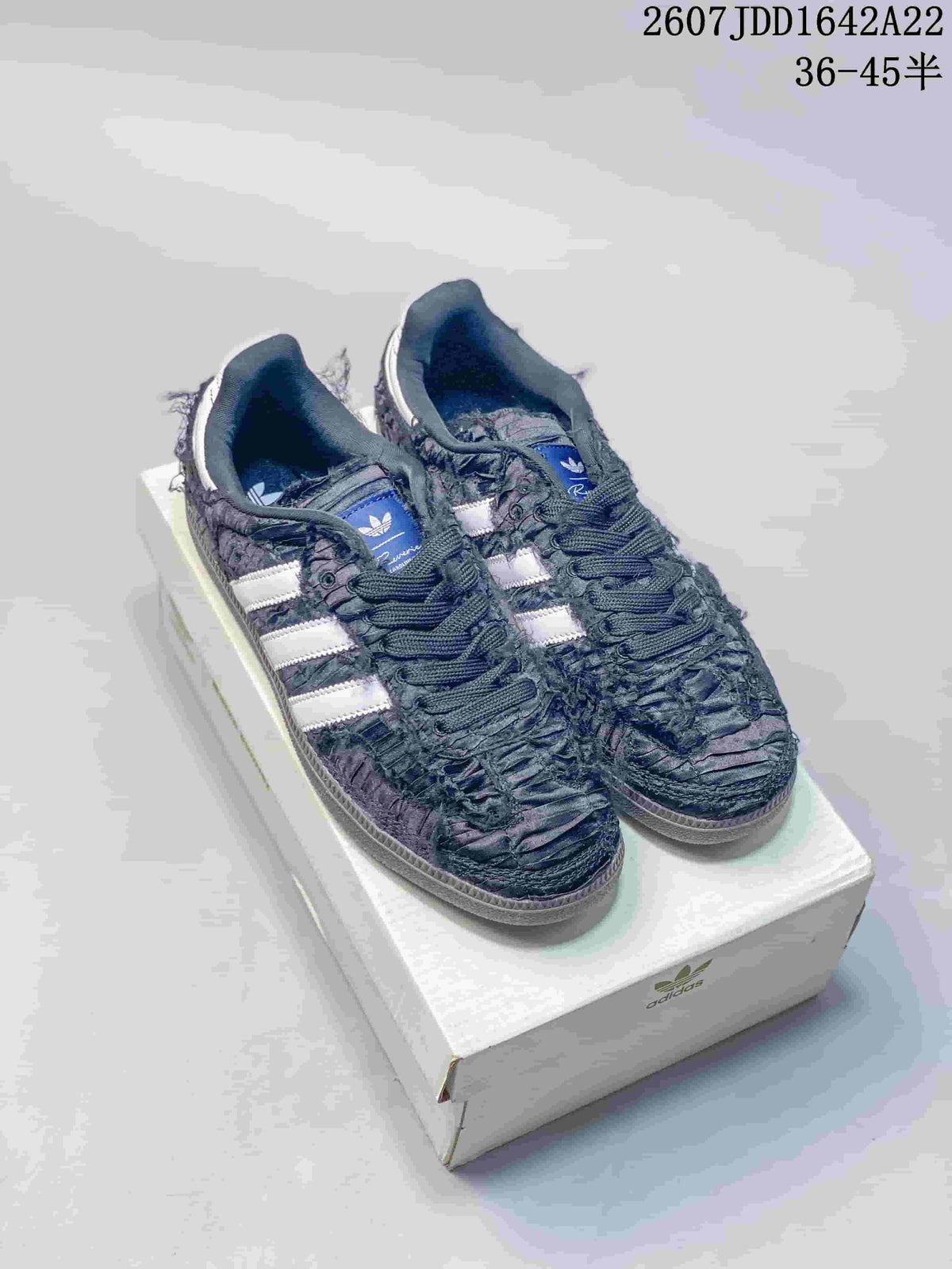 Black ruched adidas Samba OG sneakers with white contrast stripes displayed on a shoebox.