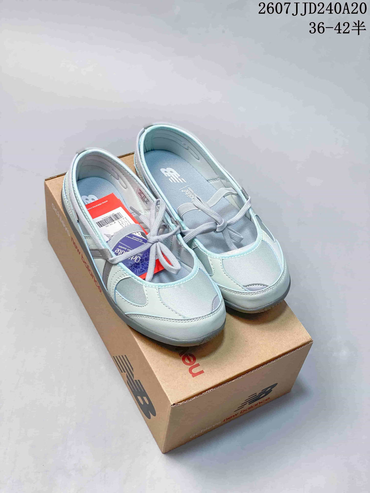 Pair of grey New Balance Flat Breeze shoes shown from above on a branded shoe box.