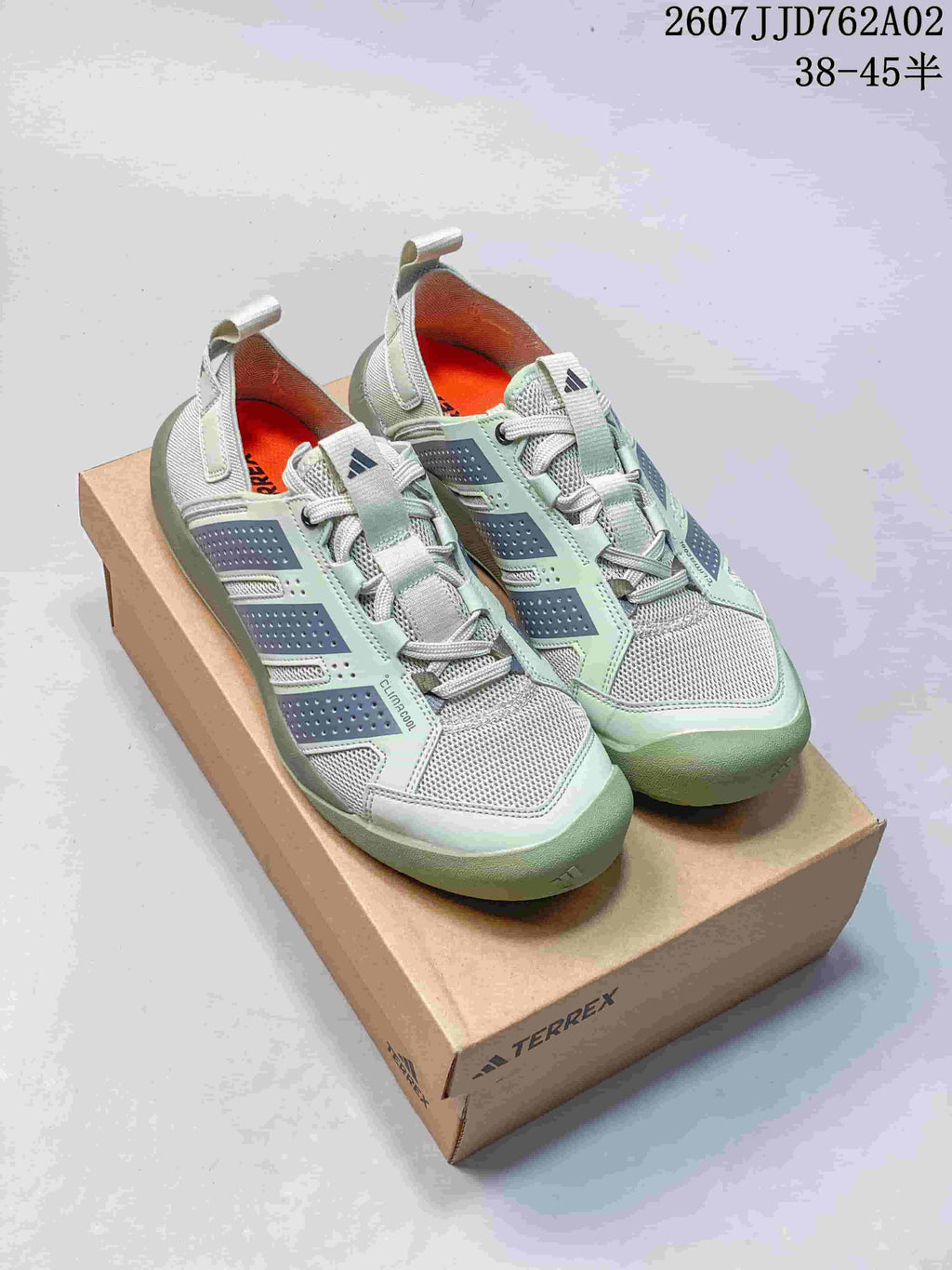 Pair of pale sage green and gray Adidas Terrex Daroga 25 shoes on a box
