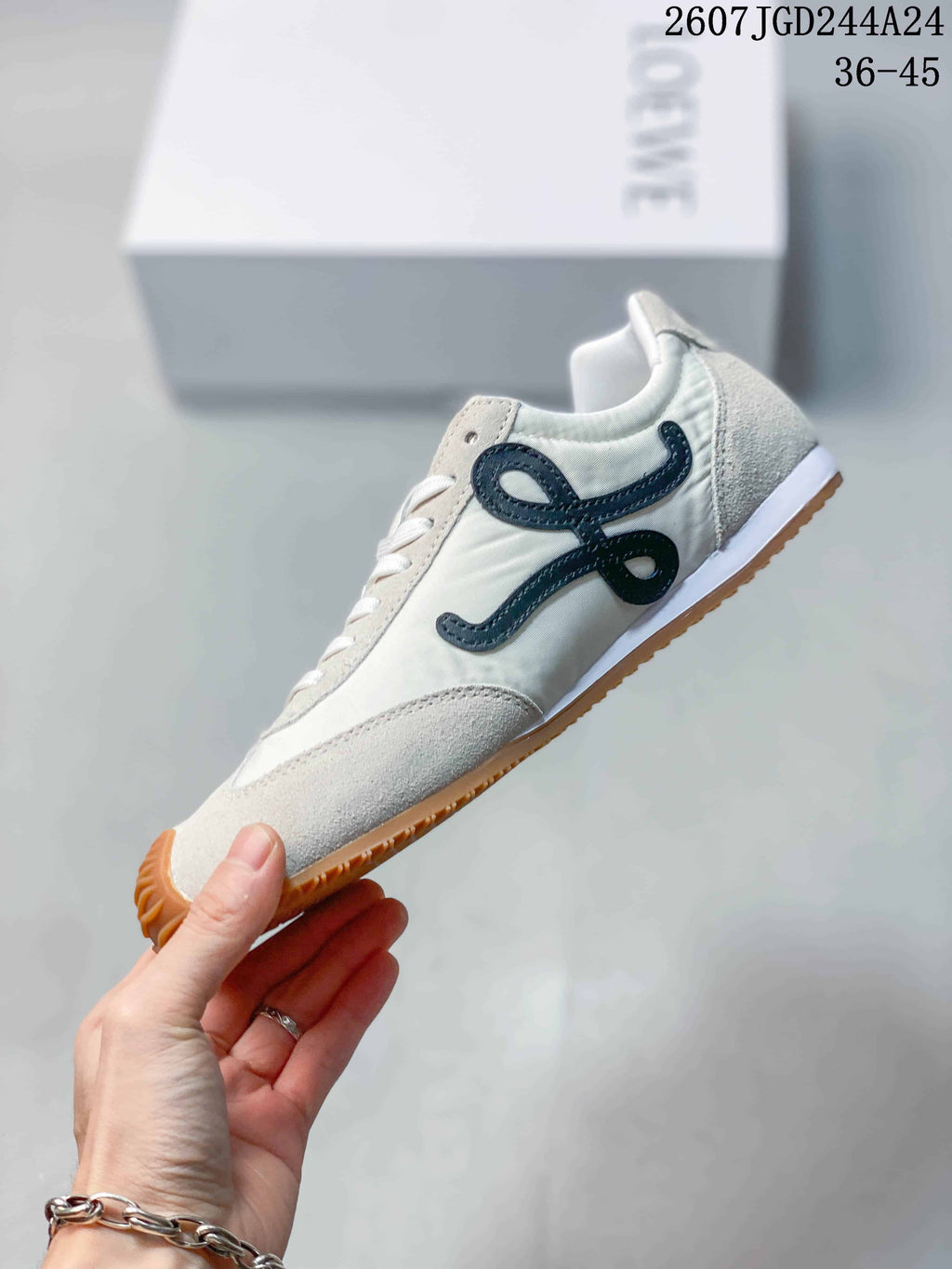 Side view of the white sneaker showing the black decorative side detail, white upper and gum outsole.