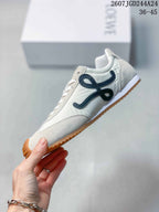 Side view of the white sneaker showing the black decorative side detail, white upper and gum outsole.