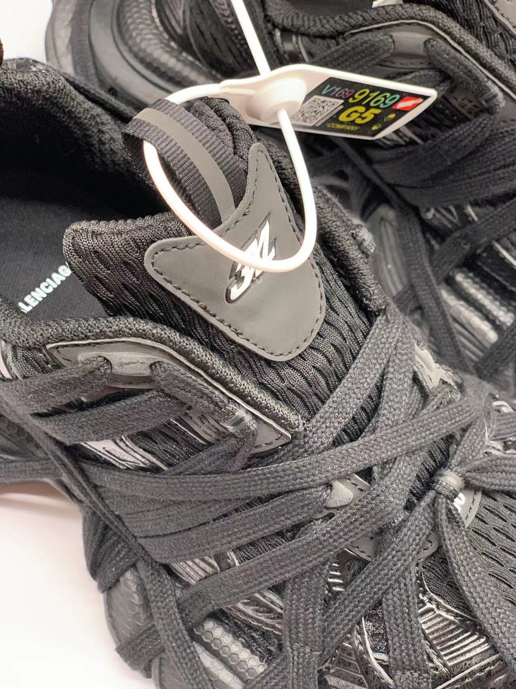 Close-up of the black upper, layered laces, textured panels, and tongue branding.