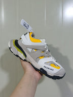 Front three-quarter view of the Balenciaga Track sneaker showing the tongue, layered upper, yellow mesh details and branded toe panel.