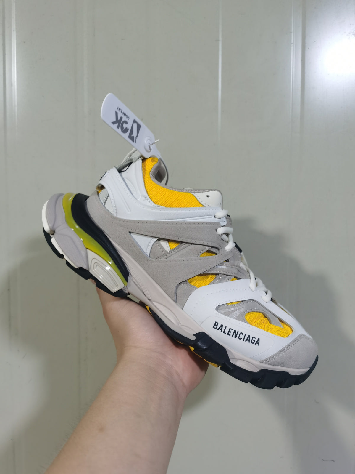 Front three-quarter view of the Balenciaga Track sneaker showing the tongue, layered upper, yellow mesh details and branded toe panel.