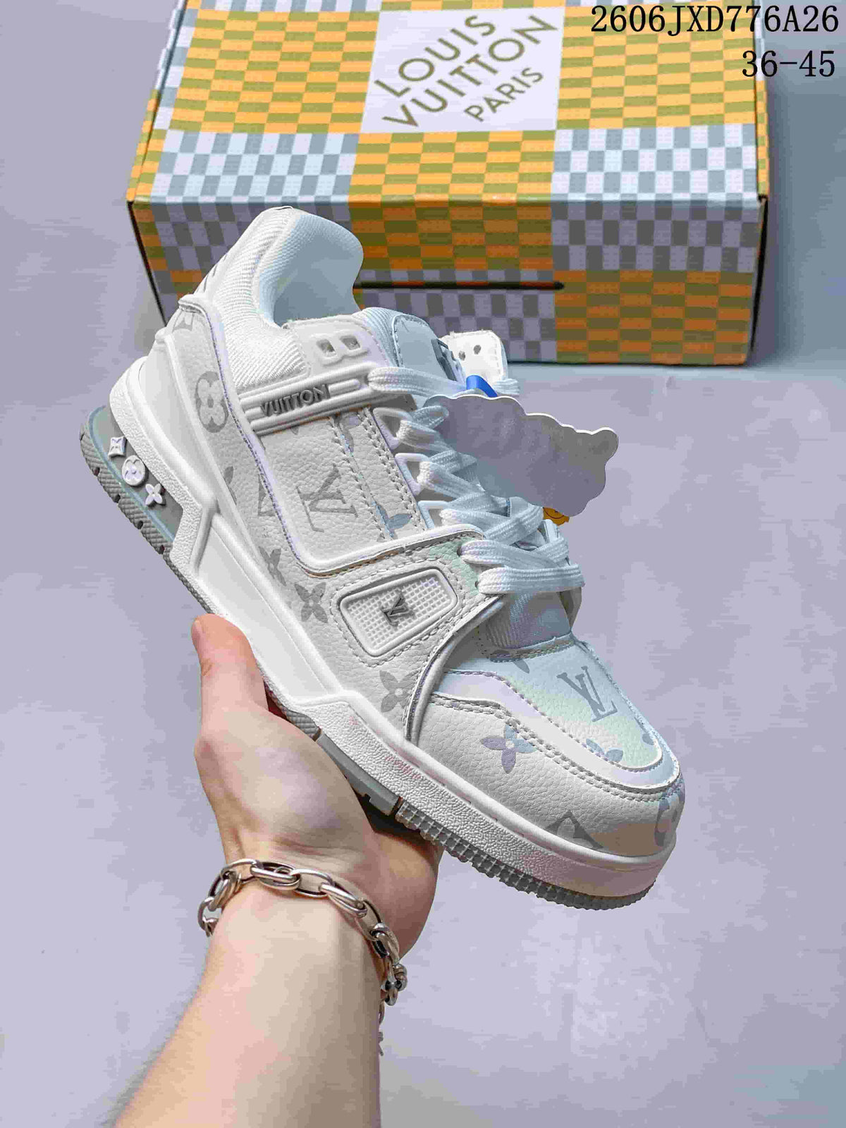 White low-top sneaker with pale multicolor monogram-style panels, shown beside a patterned box