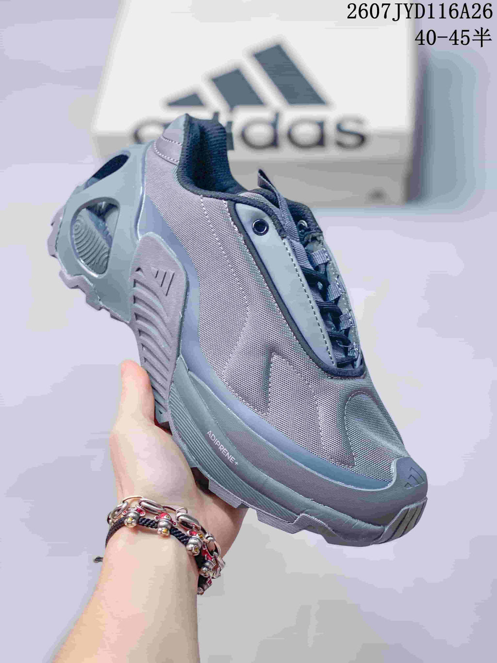 Three-quarter side view of the gray sneaker showing the layered upper, lace-up design, sculpted sole, and ADIPRENE+ marking.