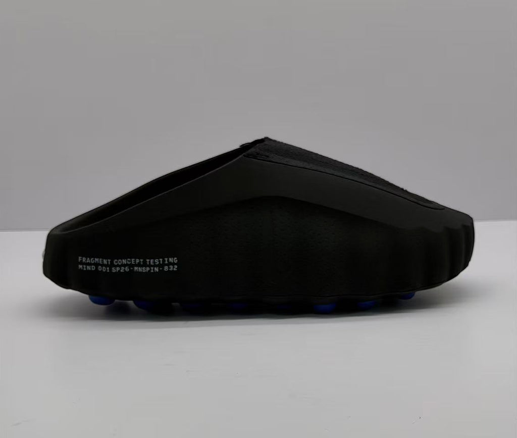 Side view of a black Nike slide sandal showing the sculpted sole and blue outsole pods.