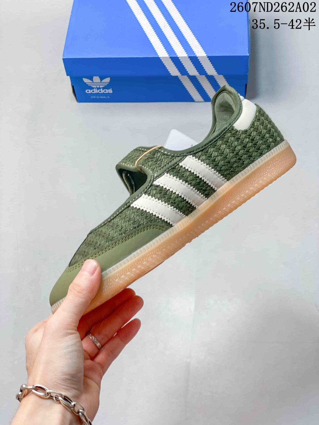 Side view of the olive-green sneaker with white stripes, crochet-style panels and gum-colored sole