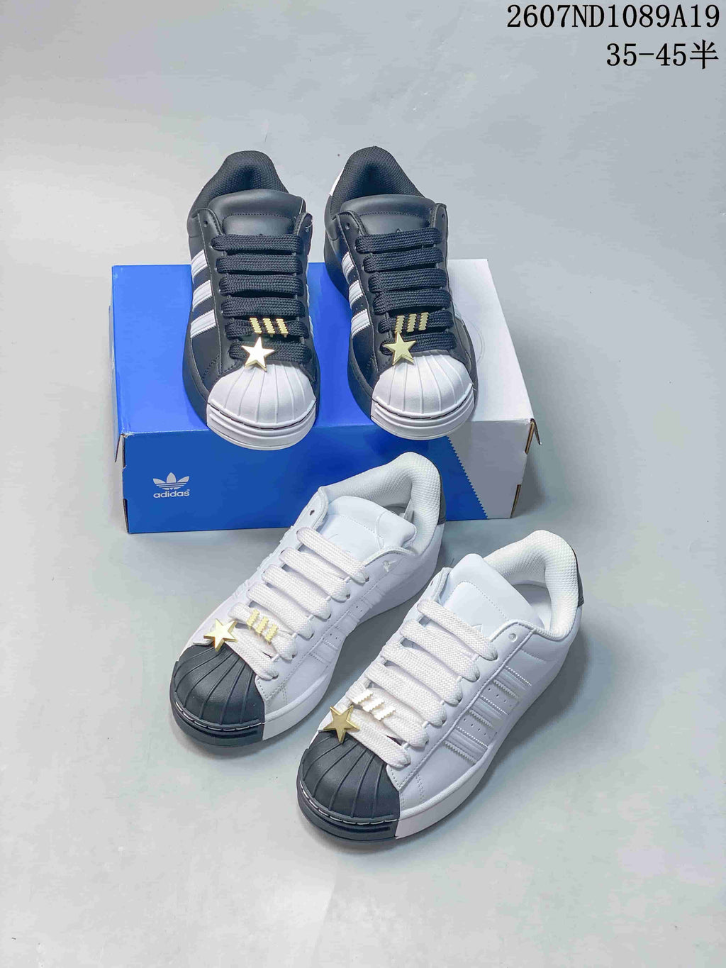 Black-and-white and white-and-dark sneaker colorways arranged around a blue adidas shoebox.