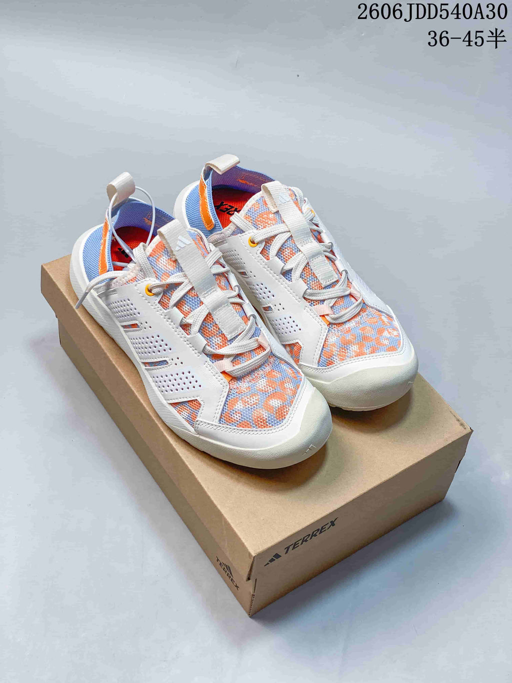 Pair of Adidas Terrex shoes with white, blue, and orange patterned uppers, shown on a box