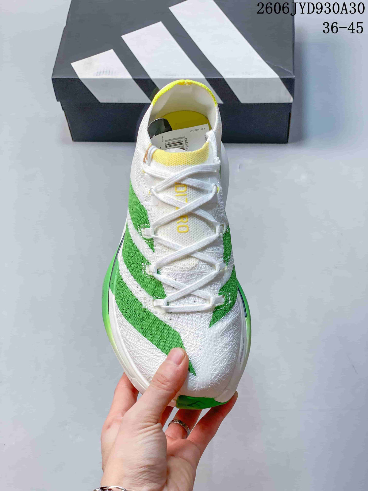 Top view of the shoe showing white laces, green stripes, and yellow collar accents.