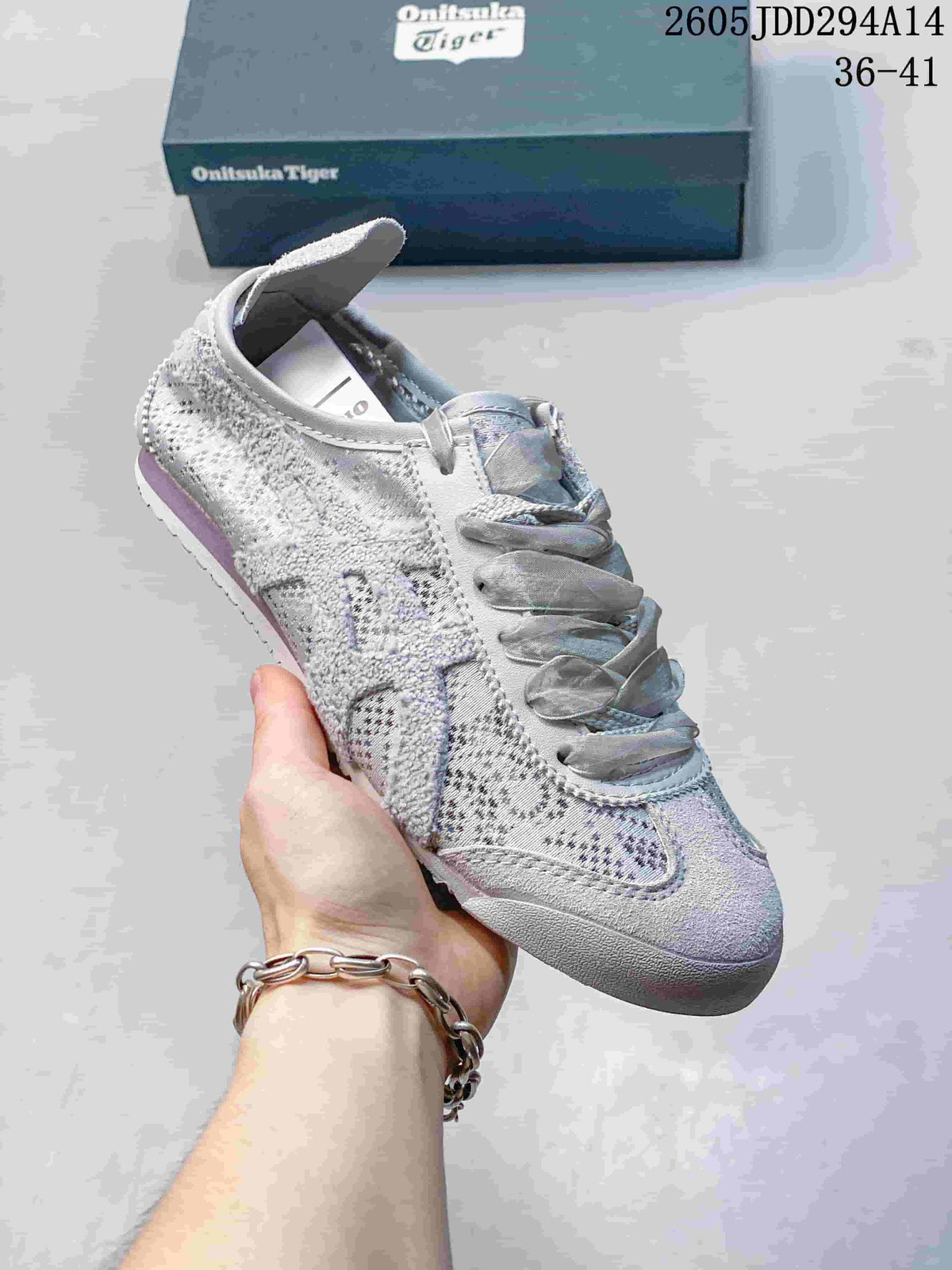 Close-up of a pale gray and lavender-toned Onitsuka Tiger sneaker with broad laces, patterned textile panels, and a textured rubber outsole.