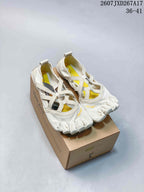 Pair of off-white Vibram five-finger training shoes displayed on a shoebox, showing the individual toe compartments and yellow interior accents.