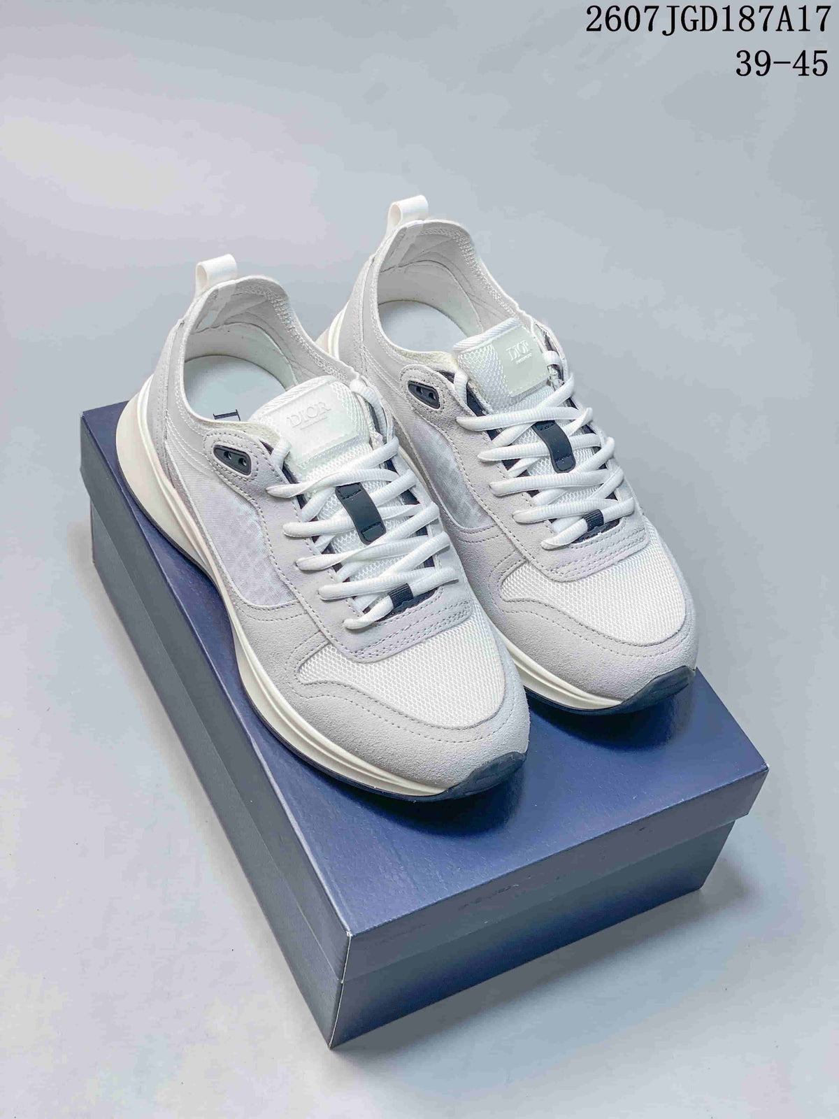 Pair of white and gray Dior B25 Runner sneakers displayed on a dark presentation box.