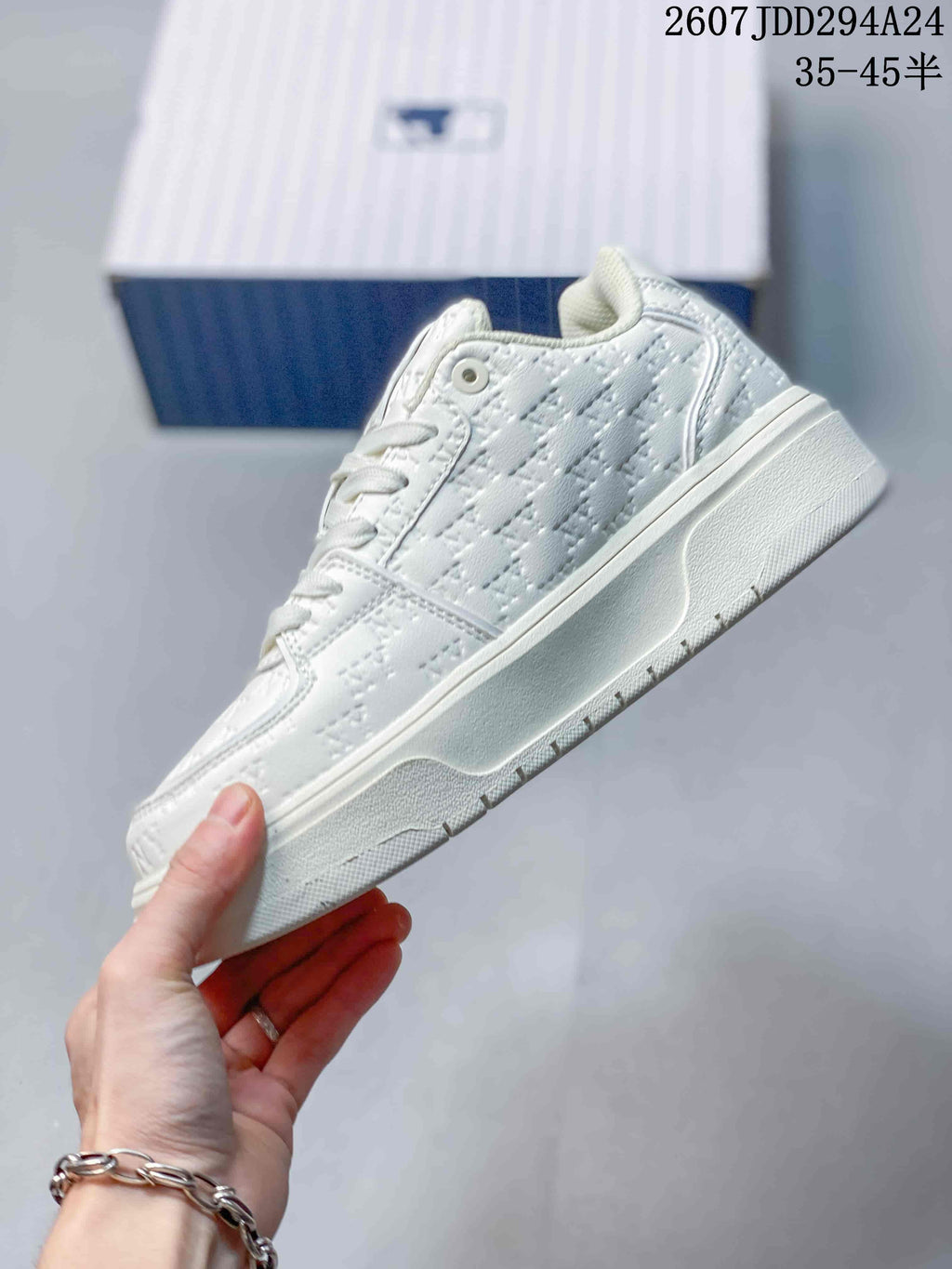 Side view of the white sneaker showing the embossed upper pattern, lace eyelet and layered platform sole.