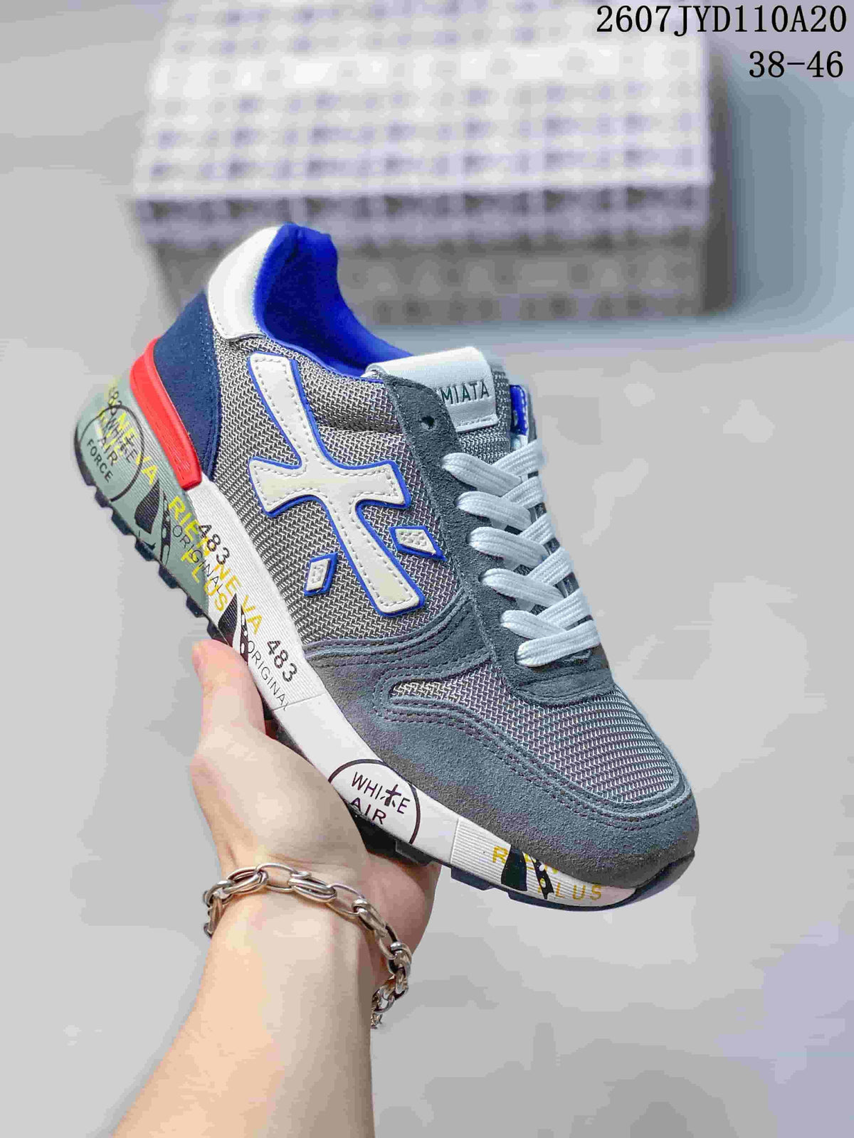 Gray Premiata sneaker with blue accents, white side detail, and a red heel accent.