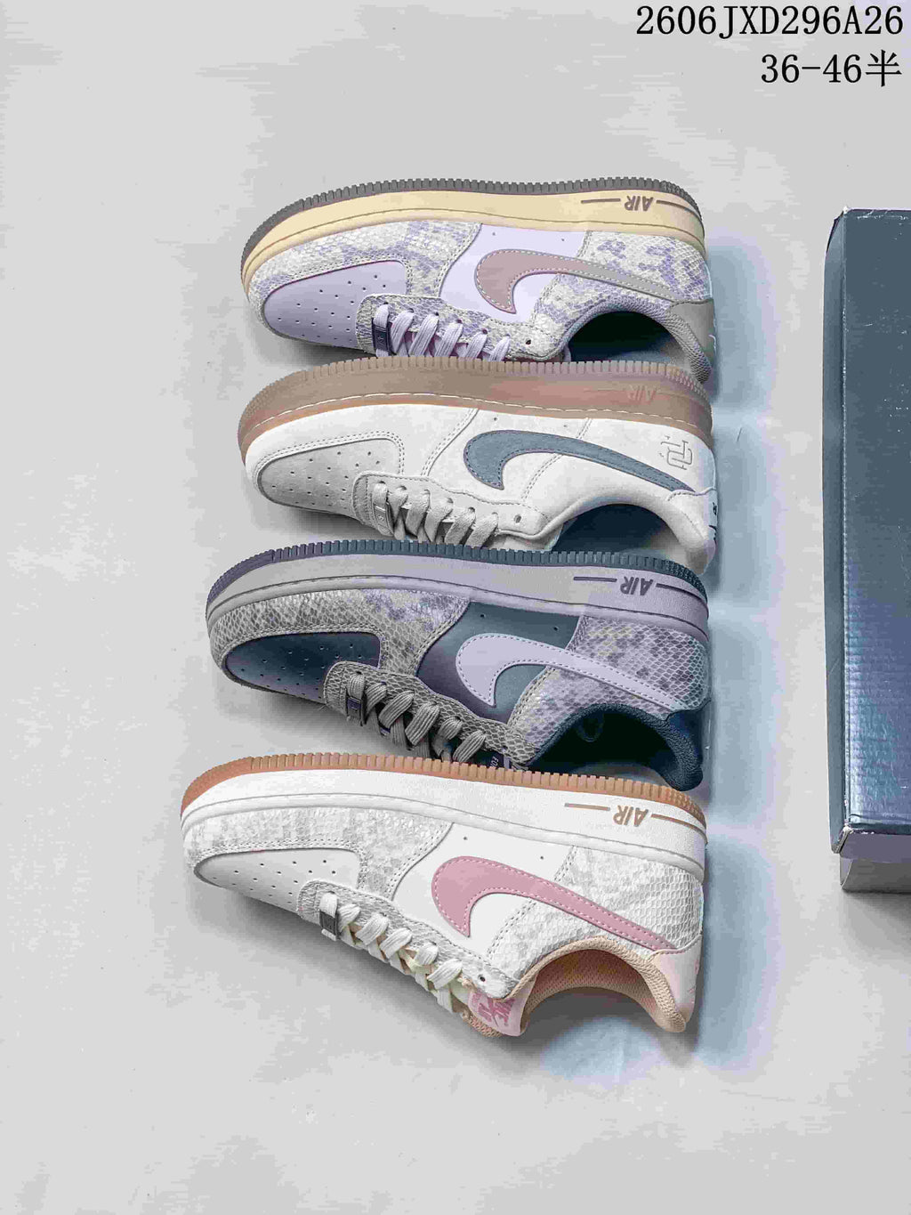 Pale gray Nike Air Force 1 sneakers with dark Swooshes, shown on a shoebox.
