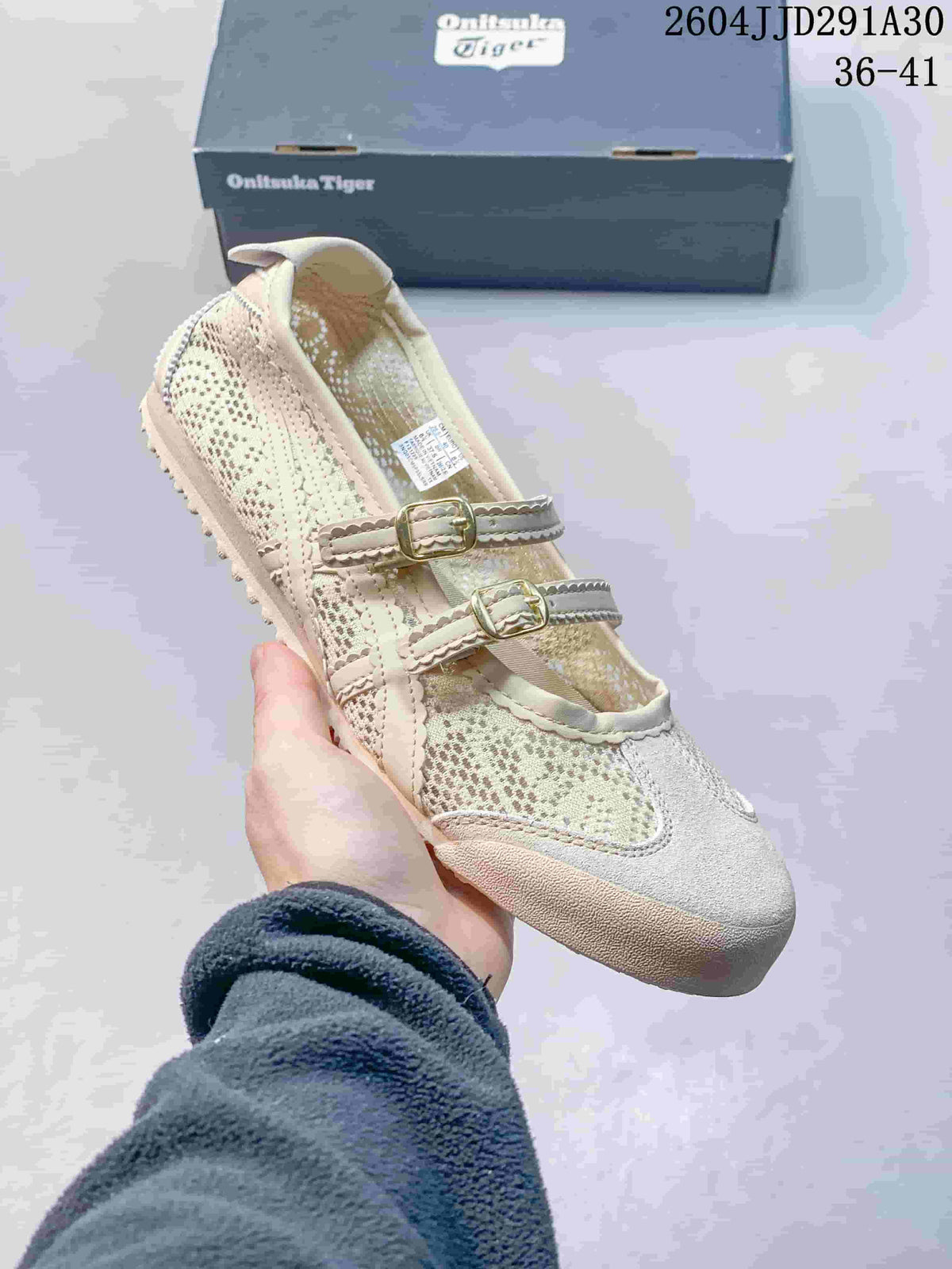 Angled close-up of the cream sneaker with patterned panels, buckle straps, and rubber sole.