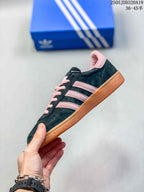 Side view showing the black upper, pink three stripes, pink collar, and gum-colored sole.