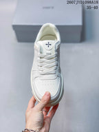Top view of the white sneaker showing the perforated toe box, white laces, and cross-shaped tongue emblem.