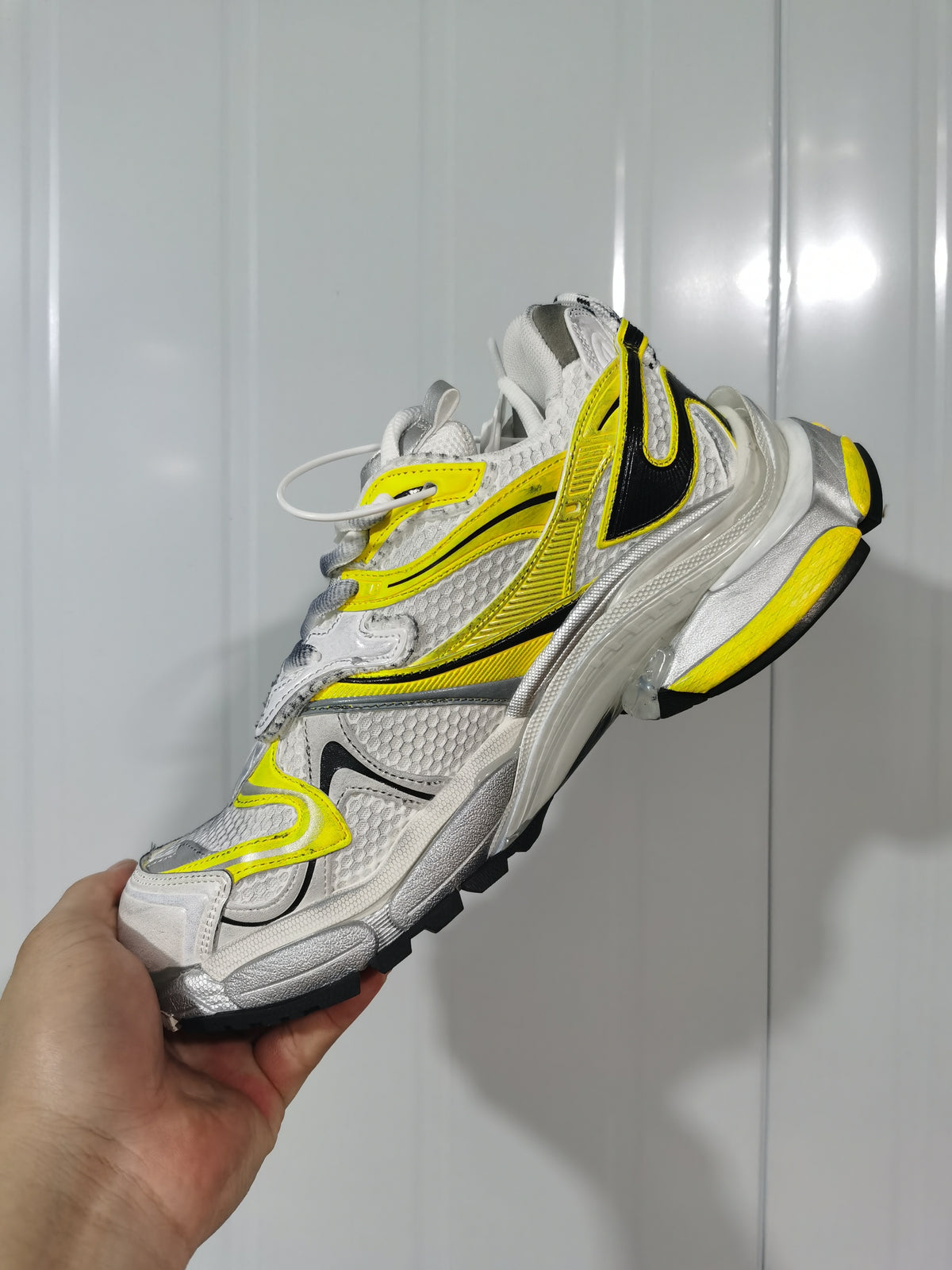 Side view of the Balenciaga Runner 2 sneaker highlighting its yellow and black overlays, silver accents and textured upper.