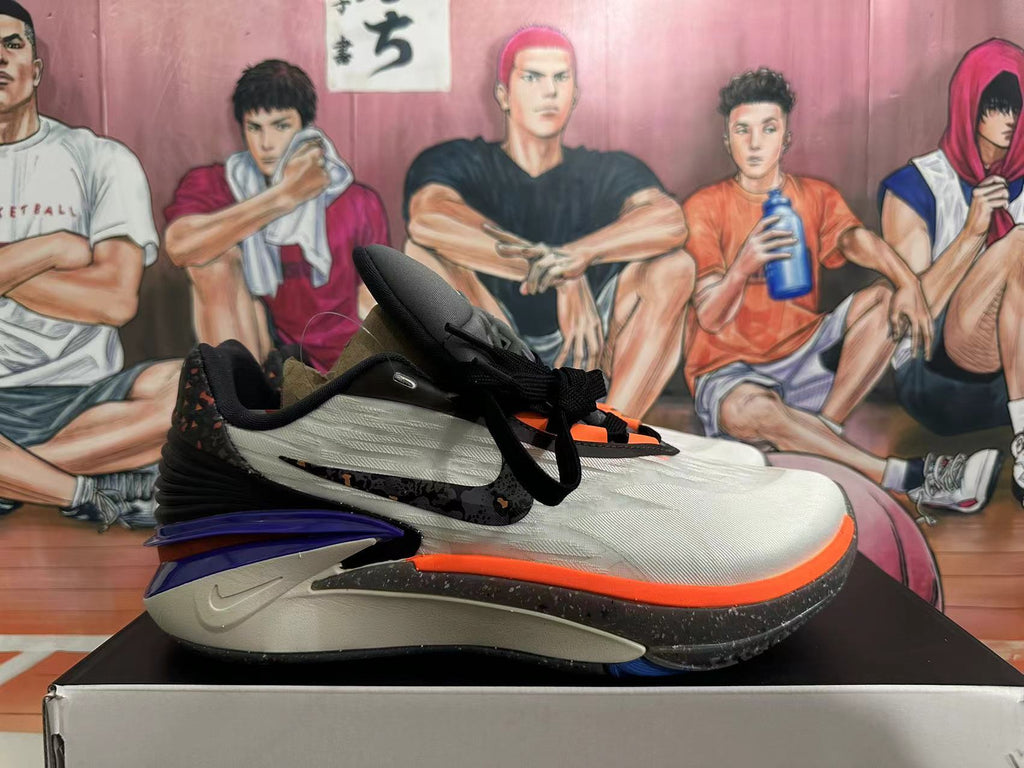 Side view of a Nike basketball shoe with gray-white panels, purple heel detail, and orange trim
