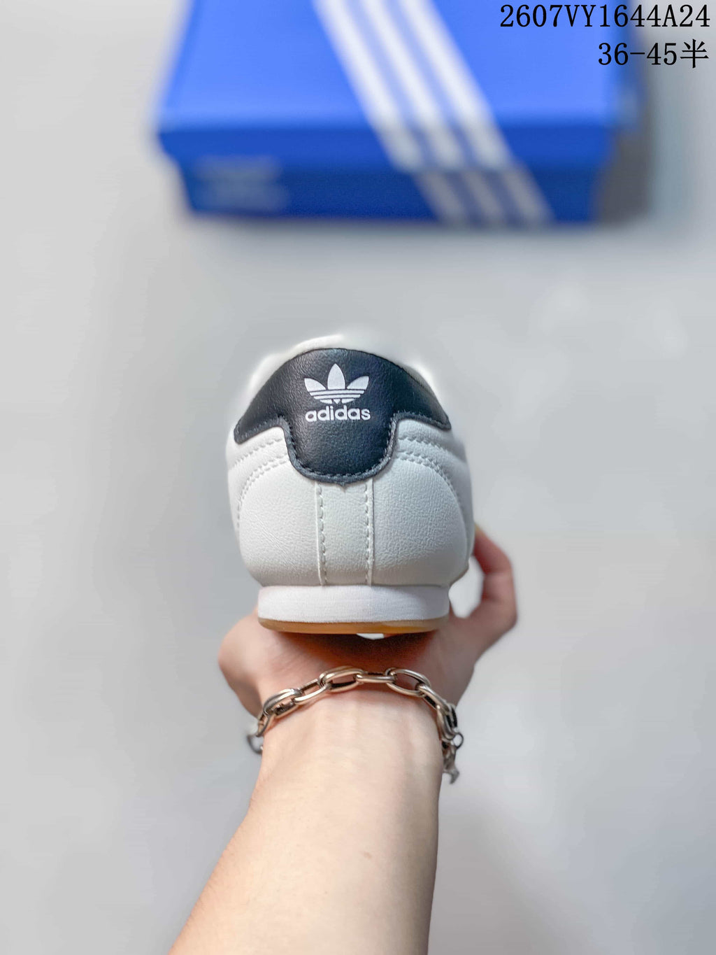 Rear view of a white adidas sneaker with a dark navy heel tab and adidas Trefoil branding.