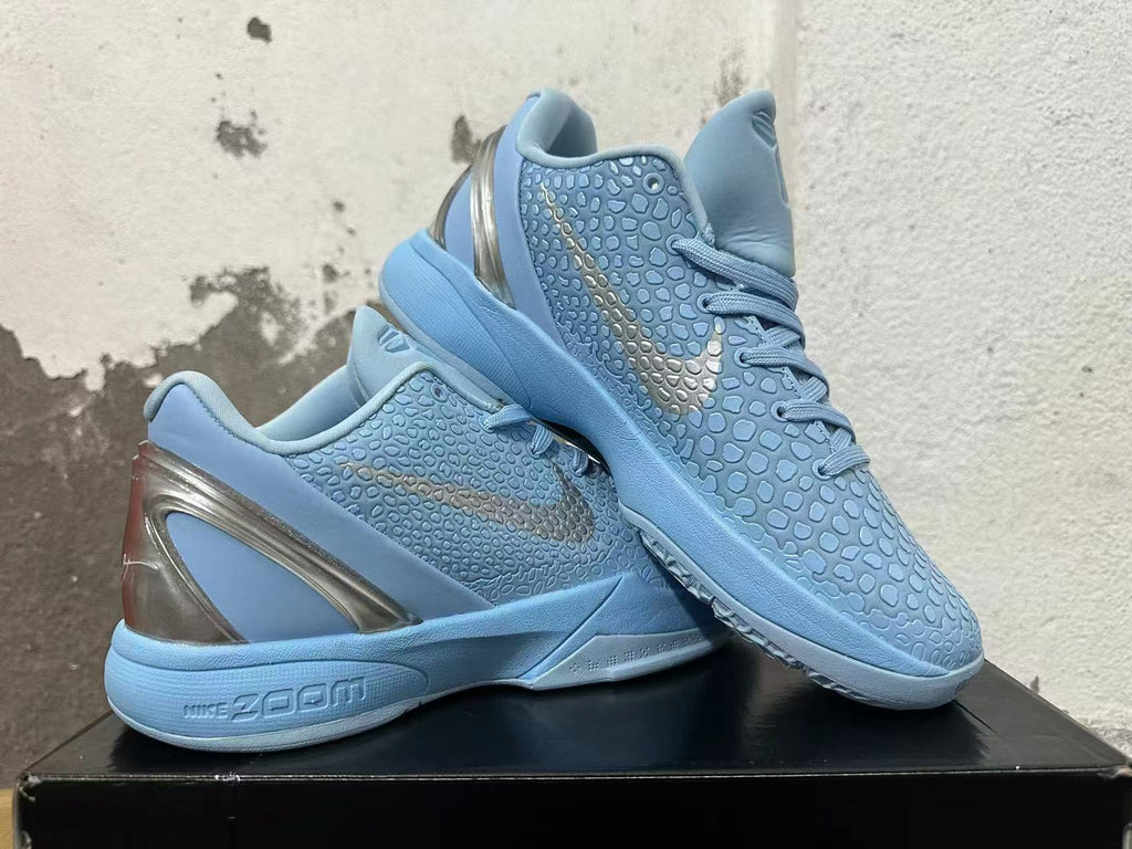Pair of light blue Nike basketball shoes displayed together, showing the textured uppers and metallic-looking heel accents.