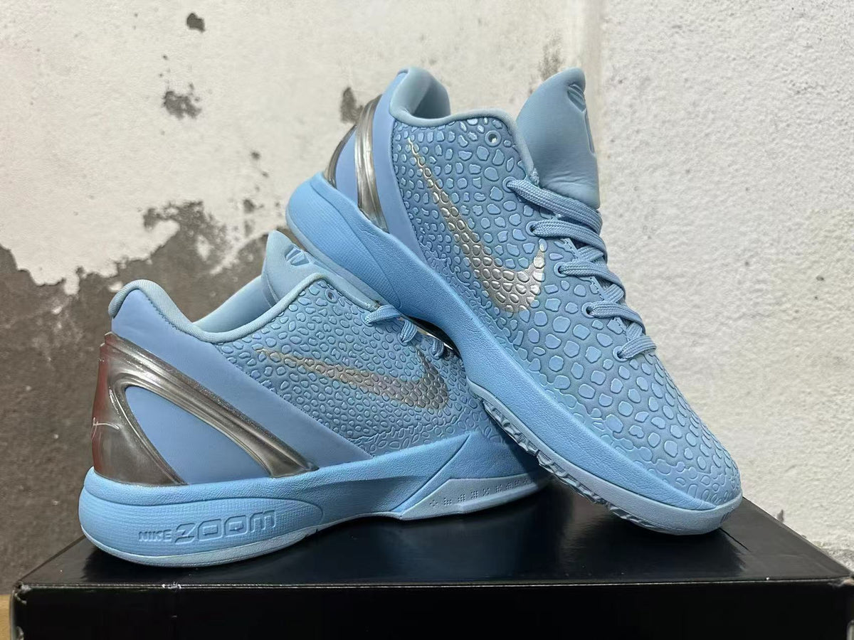 Pair of light blue Nike basketball shoes displayed together, showing the textured uppers and metallic-looking heel accents.