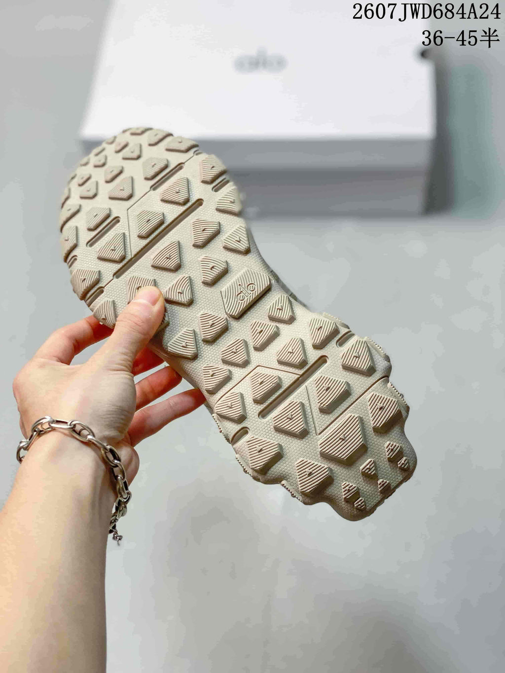 Close-up of the sneaker outsole showing a textured lug-style tread pattern and Alo branding.