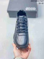 Front view of the sneaker showing the rounded toe, woven laces, tongue branding, and tonal dark finish.