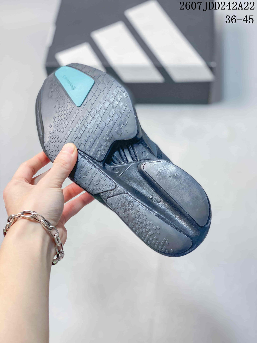 Underside view showing the black outsole with geometric patterned tread and a turquoise heel section.