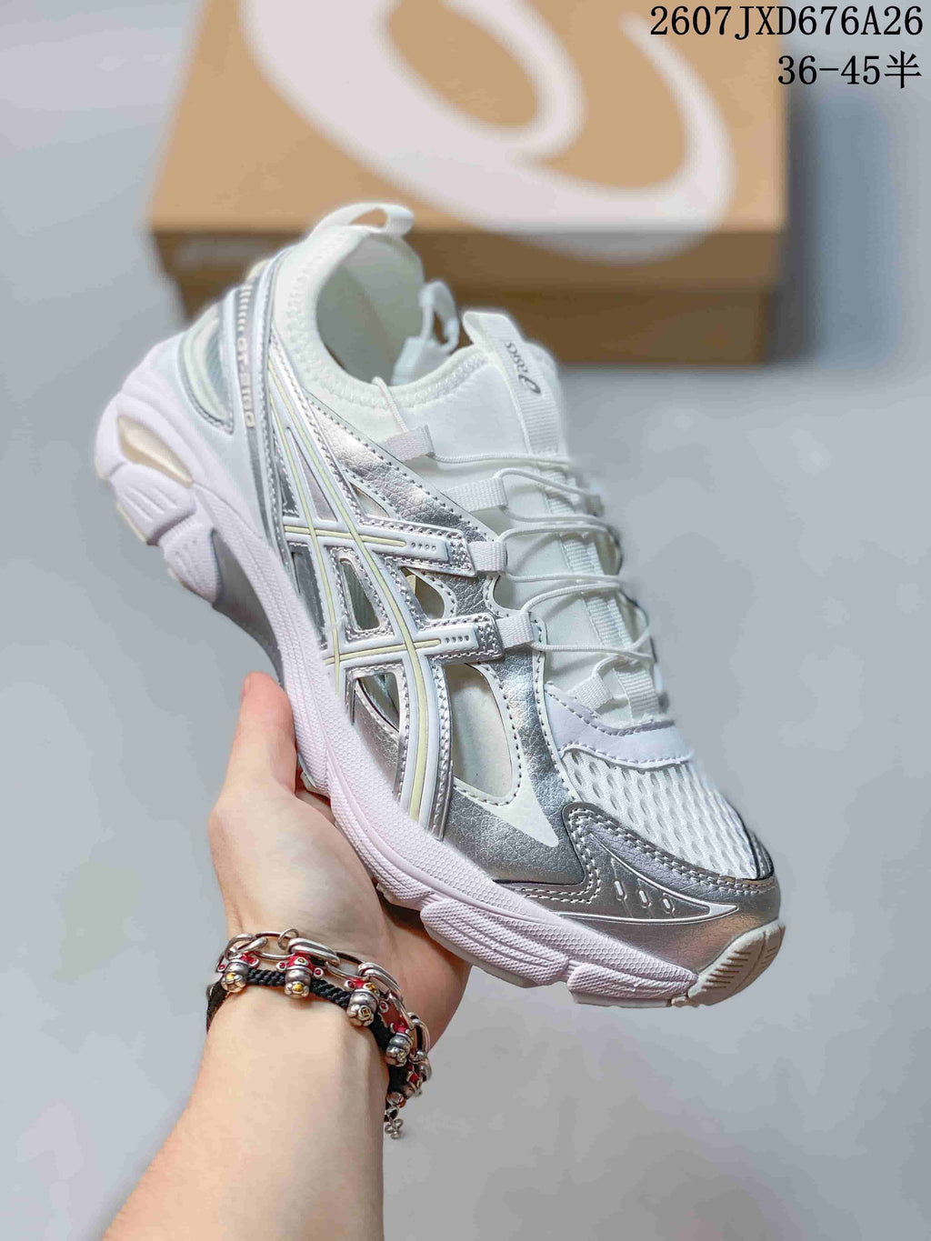 Angled side view of the white and silver ASICS sneaker showing the layered upper, metallic-look overlays, and segmented sole.